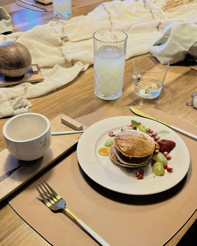 Un plato servido en la mesa larga, con taza, cubiertos y limonada