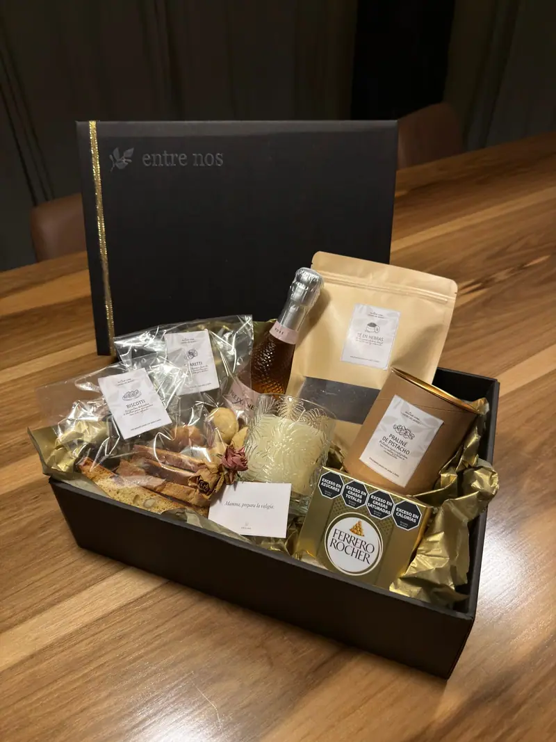 Caja de regalo Entre Nos con biscotti, amaretti, espumante, té en hebras, praliné de pistacho y una vela
